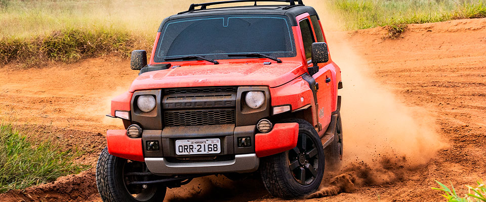 Foto de um Troller T4 vermelho girando as rodas traseiras na lama